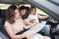 Three friends and a dog are traveling in the car. Women look at a paper map and plan a route while on vacation Royalty Free Stock Photo