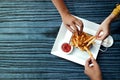 Three Friends Eating French Potato Fries, Serve on Metal Mesh Flying Sieve with Two Dipping Sauce. Lay on Wooden Table. High Angle