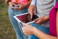 Three friends with electronic gadget in park. Close up.