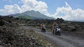 Three friends on a fun scooter trip taking a picture in front of large volcano