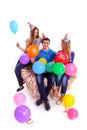 Three friends with hats and balloons sitting on the couch Royalty Free Stock Photo