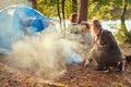 Three friends hiking in the forest and try to light a fire at camp. Royalty Free Stock Photo