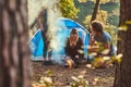 Three friends hiking in the forest and try to light a fire at camp. Royalty Free Stock Photo