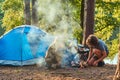 Three friends hiking in the forest and try to light a fire at camp. Royalty Free Stock Photo