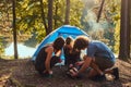 Three friends hiking in the forest and try to light a fire at camp. Royalty Free Stock Photo