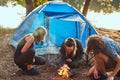 Three friends hiking in the forest and try to light a fire at camp. Royalty Free Stock Photo