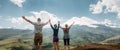 Three friends joined hands and raised their hands up, enjoying the view of the mountains in the summer. Lifestyle Travel Happy