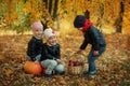 Three friends kids in autumn leaves with pumpkins and apple