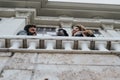 Three friends laughing and sharing joyful moments on a city balcony. Royalty Free Stock Photo