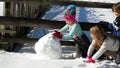 Three Friends are Making a Huge Snowball Together. Closeup Portrait of Two Girls and One Boy Playing Ourdoors in the