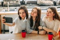 Three friends making selfie drink coffee at cafe Royalty Free Stock Photo