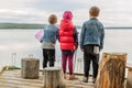 Three friends play fishing on wooden pier near pond. Two toddler boys and one girl at river bank. Children having fun with sticks Royalty Free Stock Photo