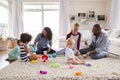 Three friends playing with toddlers on sitting room floor Royalty Free Stock Photo