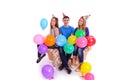 Three friends sitting on a couch with balloons and hats Royalty Free Stock Photo