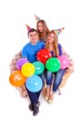 Three friends sitting on a couch with hats and balloons Royalty Free Stock Photo