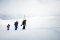 Three friends snowboarders skiers go uphill with a snowboard and skis in their hands for backcountry or freeride Royalty Free Stock Photo