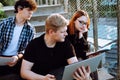 Three friends studying with laptop outdoors sitting on stairs. Small group of high school people preparing for exam. Royalty Free Stock Photo