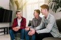 Three friends talking at green sofa in living room. Guys having a talk, gossip