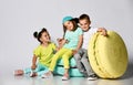 Three friends of triplets - two girls and a boy in bright clothes have fun at the birthday party room decoration candy macarons