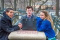 Three friends, two men and one woman, sitting outdoors in winter, talking