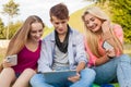 Three friends watching funny movies on tablet pc in park.