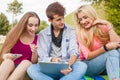 Three friends watching funny movies on tablet pc in park.