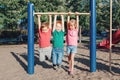 Three funny Caucasian friends hanging on pull-up bars in park on playground. Summer outdoors activity for kids. Active children Royalty Free Stock Photo