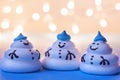 Three funny meringue snowmen under a festive garland.