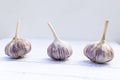 Three garlics on a white wooden table. Folk remedy for increasing immunity. Useful fruit from the garden