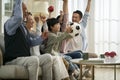 Three generation asian family watching soccer game telecast on tv together at home Royalty Free Stock Photo