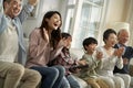 Three generational asian family watching sports game on tv and cheering Royalty Free Stock Photo