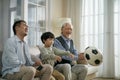 Three generation asian family watching soccer game telecast on TV Royalty Free Stock Photo