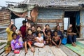 Three generation of Bajau tribe sit outside waving hands outside their wooden hut.