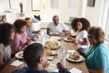 Three generation African American family sitting at the table talking and eating dinner together, close up