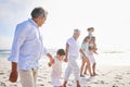 Three generation family on vacation holding hands while walking along the beach together. Mixed race family with two Royalty Free Stock Photo