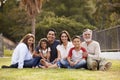Three generation Hispanic family sitting on the grass in the park smiling to camera, selective focus Royalty Free Stock Photo