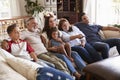 Three generation Hispanic family sitting on the sofa watching TV, grandmother using remote control Royalty Free Stock Photo