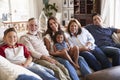 Three generation Hispanic family sitting on the sofa watching TV, looking to camera Royalty Free Stock Photo