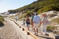 Three generation white family walking together along a wooden promenade on a beach, full length Royalty Free Stock Photo