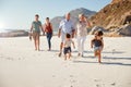 Three generation white family walking together on a sunny beach, kids running ahead Royalty Free Stock Photo