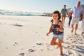 Three generation white family walking together on a sunny beach, young daughter running ahead Royalty Free Stock Photo