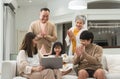 Three generations of Asian family, grandmother, grandfather, father, mother, little cute daughter using laptop, relaxing together Royalty Free Stock Photo