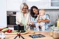 Three Generations Family. Grandma, mother and baby record a cooking vlog or podcast while chopping vegetables for a healthy Royalty Free Stock Photo