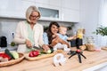 Three Generations Family. Grandma, mother and baby record a cooking vlog or podcast while chopping vegetables for a healthy Royalty Free Stock Photo