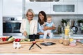 Three Generations Family. Grandma, mother and baby record a cooking vlog or podcast while chopping vegetables for a healthy Royalty Free Stock Photo