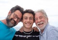Three generations of family, hug smiling happy, father, teenage son and grandfather. Handsome people having fun together