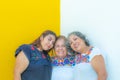 Three generations of Mexican women smiling, granddaughter and daughter leaning on the mother in floral print blouses Royalty Free Stock Photo