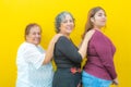 Three generations of smiling Mexican women wearing casual clothes in a row holding their shoulders and looking at the camera Royalty Free Stock Photo