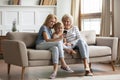 Three generations of women sitting on sofa using smartphone Royalty Free Stock Photo