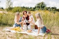 Three generations of women of the same family drink tea from mugs during a picnic in the park or on the lawn Royalty Free Stock Photo